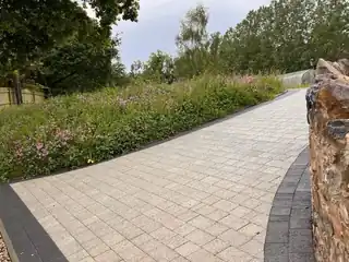 Block-paved path beside a flint wall and meadow planting